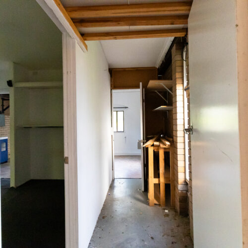 Hallway before renovation at 14 Sunshine Boulevard, Broadbeach Waters - dated timber beams and concrete floors