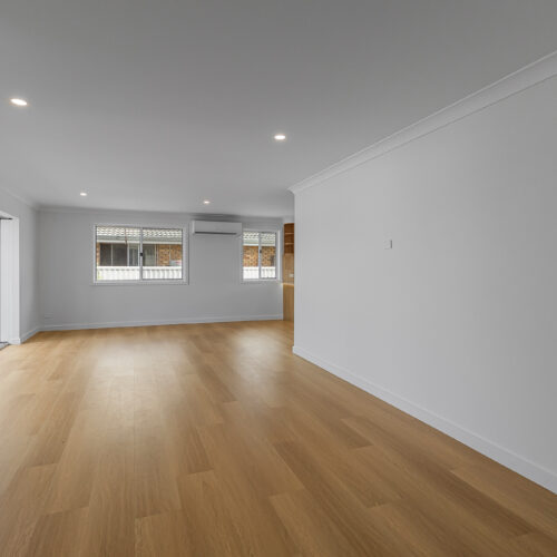 Modern open-plan living room after renovation at 14 Sunshine Boulevard, Broadbeach Waters by Steedbuilt - engineered timber floors and grey feature wall