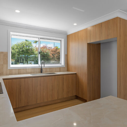 Modern kitchen with timber cabinetry and stone benchtops at 14 Sunshine Boulevard, Broadbeach Waters by Steedbuilt