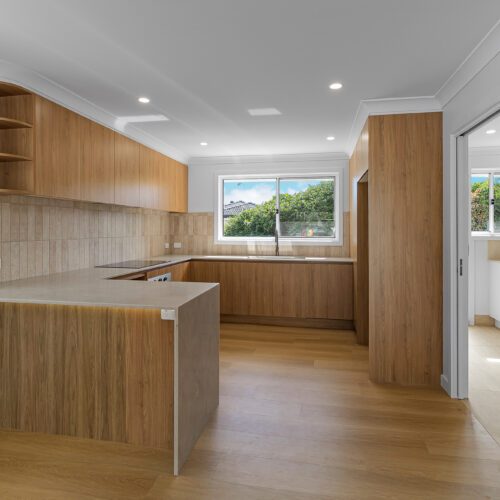 Modern white kitchen after renovation at 14 Sunshine Boulevard, Broadbeach Waters by Steedbuilt - stone benchtops and engineered flooring